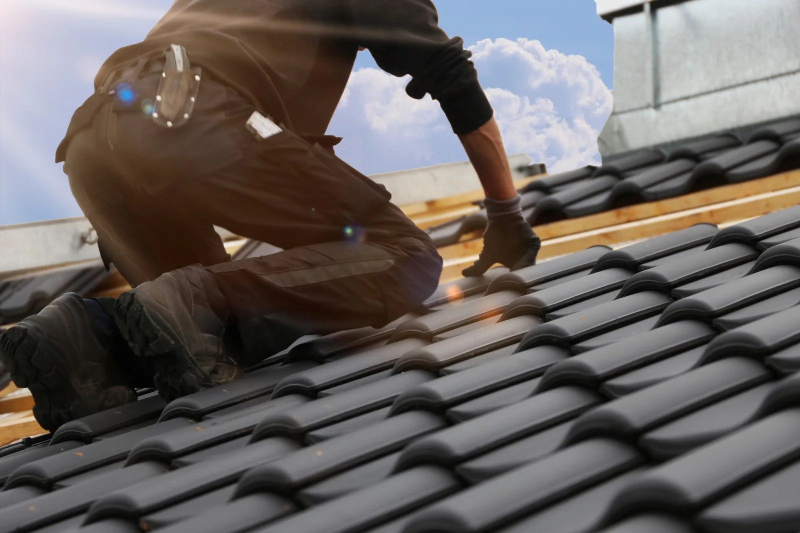 Dachdecker bei der Arbeit auf einem Steildach mit dunklen Dachziegeln